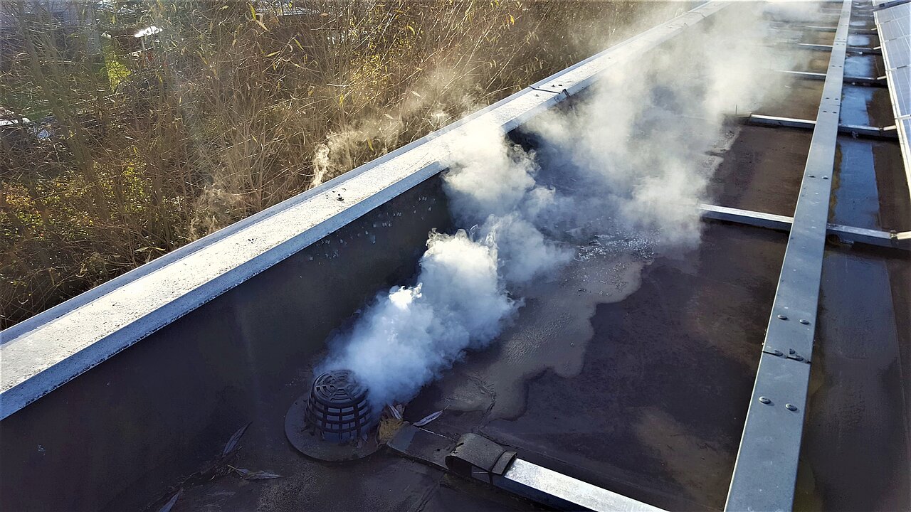 An der undichten Stelle des Ablaufs tritt Rauchgas aus Rauchgas tritt aus dem defekten Ablauf des Daches aus.